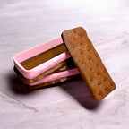 Two ice cream sandwiches with pink and brown colors on a marble surface