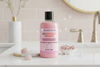 Pink bottle of Grapefruit Mango body wash with black cap on a white background
