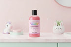 Pink bottle of 'Mysterious Rainbow' body wash with colorful text on a white background