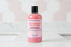 Pink bottle of strawberry shortcake body wash with a black cap on a white background