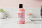 Pink bottle of strawberry soda pop body wash with a black cap on a pink background